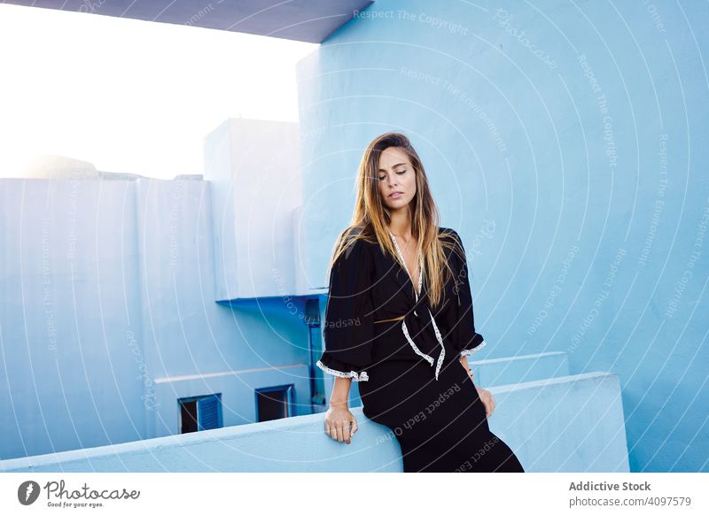 Frau lehnt sich an modernes blaues Gebäude an lange Haare Kleid schwarz elegant Stehen Konstruktion Struktur geometrisch Architektur urban Fassade Zentrum Wand
