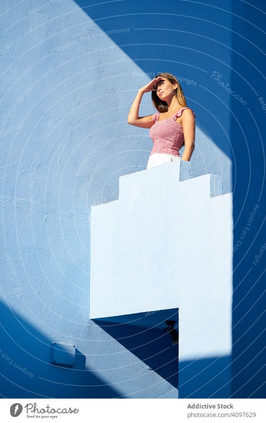 Frau steht auf der Spitze eines blauen Gebäudes lange Haare lässig elegant Konstruktion Treppe Struktur geometrisch Architektur urban Fassade Stadtzentrum