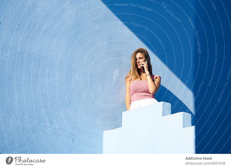 Frau auf einem blauen Gebäude mit Smartphone lässig elegant Konstruktion Treppe Struktur geometrisch Architektur urban Fassade Wand abstrakt Irrgarten