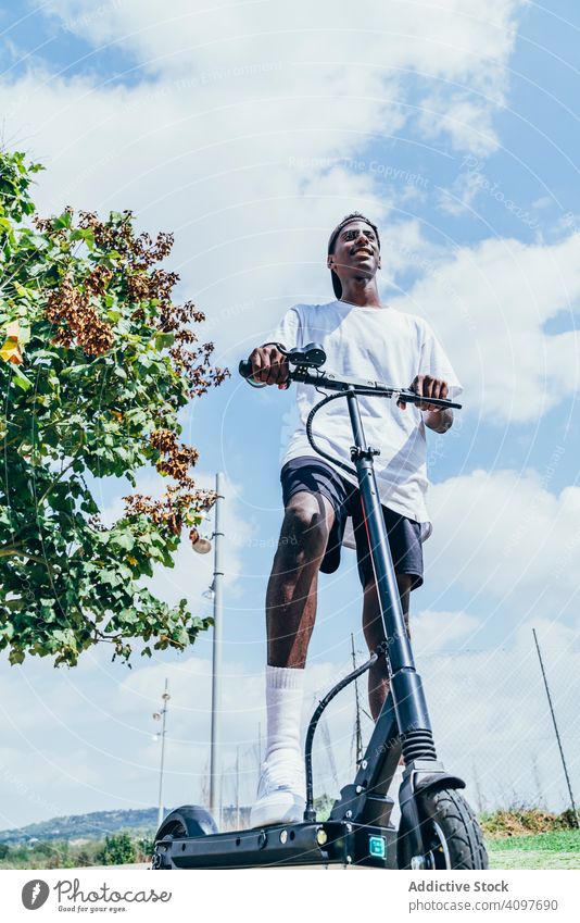 Schwarzer Mann fährt auf Elektroroller im Park elektrisch modern schwarz Gleichgewicht Rad Afroamerikaner Bewegung Tretroller Transport Großstadt trendy Körper
