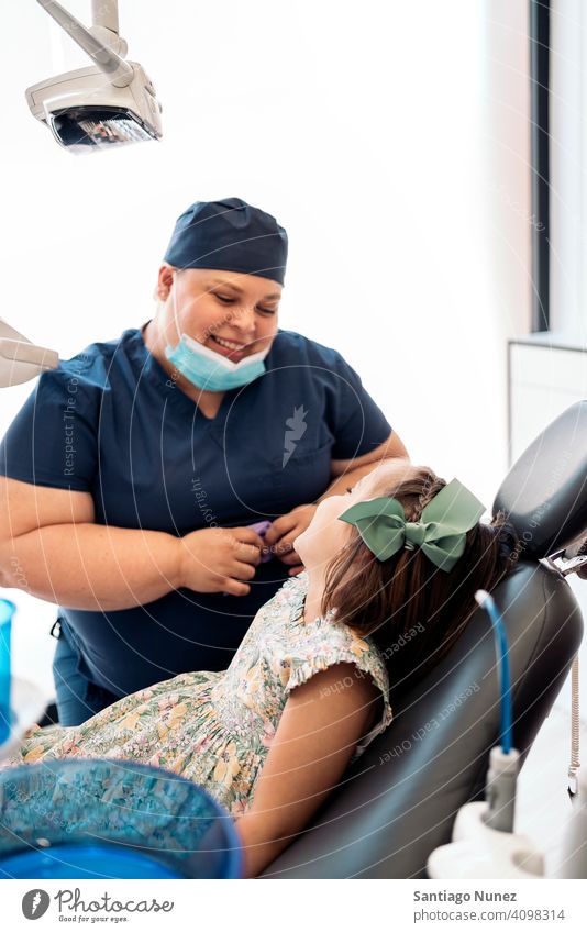 Glückliche Mitarbeiterin der Zahnklinik und kleines Mädchen die sich gegenseitig ansehen Frau Arbeiter geduldig Dentalklinik Lächeln Zwei Personen Seitenansicht
