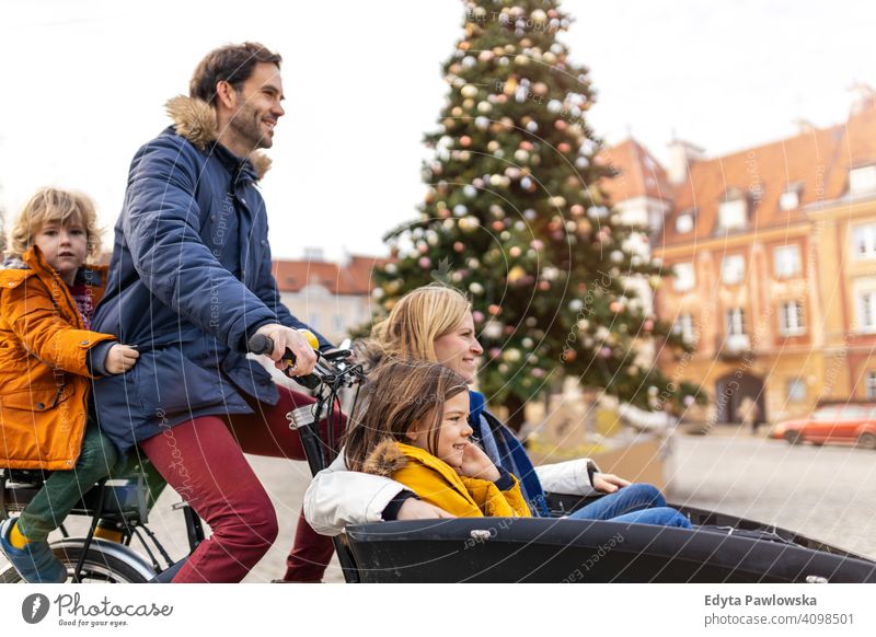 Junge Familie fährt in einem Lastenfahrrad während Weihnachten Lastenrad Fahrrad Fahrradfahren Verkehr Dreirad Gesundheit aktiv Zyklus Radfahren modern