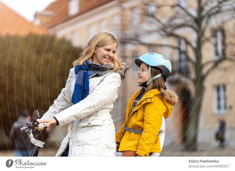 Junge Frau und ihr Sohn fahren mit dem Fahrrad in einer Stadt jung tragend Schutzhelm Fahrradfahren Winter Herbst Mutter Familie Eltern Verwandte Kind Kinder