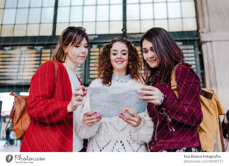 Gruppe von drei jungen kaukasischen Frauen am Bahnhof lesen eine Karte. Reisen und Freundschaft Konzept reisen Freunde Landkarte Zusammensein Spaß 3 Holzplatte