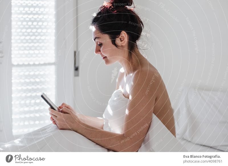 attraktive junge kaukasische Frau entspannt gut im Bett während der Morgenzeit. Dame mit Mobiltelefon im Schlafzimmer Handy Technik & Technologie Kaukasier