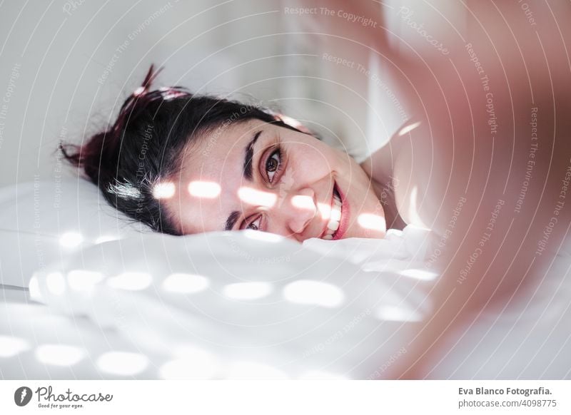 Porträt der attraktiven jungen kaukasischen Frau entspannt im Bett während der Morgenzeit. Dame genießt frische weiche Bettwäsche Bettwäsche und Matratze im Schlafzimmer