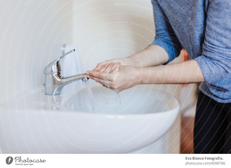 Nahaufnahme einer kaukasischen Frau, die sich im Badezimmer die Hände wäscht, um eine Covid-19-Virusinfektion zu verhindern. Empfohlenes Waschen mit Seife und fließendem Wasser während einer Coronavirus-Pandemie