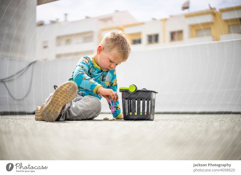 Kleiner Junge spielt mit bunten Wäscheklammern auf dem Dach seines Wohnhauses spielen Pflöcke Kleidung Zapfen Sperrung farbenfroh Spiel Spaß Spielzeug klein