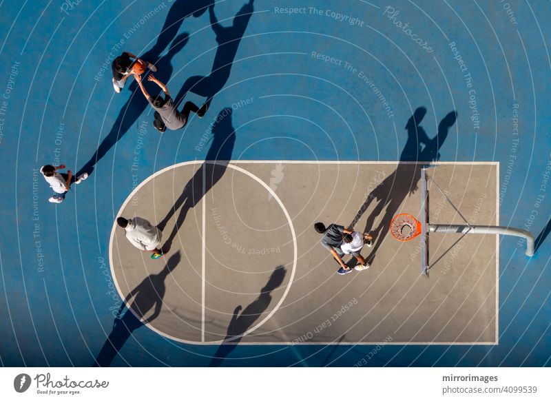 junger Mann spielt Basketball in der Abenddämmerung oder Morgenlicht mit langen Schatten hohen Winkel Vogelperspektive Basketballkorb mit Netz