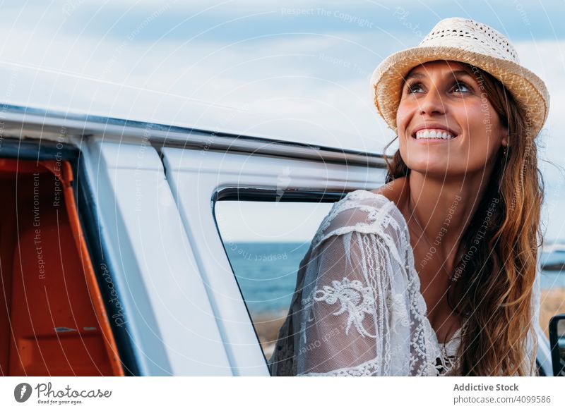 Lächelnde Frau mit Hut auf dem Vordersitz eines sich öffnenden Autos PKW Strand Tourismus reisen Freiheit Fahrzeug Verkehr freudig Erholung charmant Vergnügen