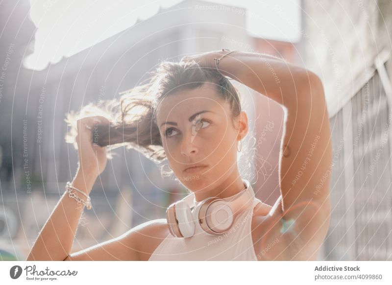 Brünette beim Musikhören im Sonnenlicht Frau Kopfhörer Straße Porträt reisen schlendern Körperhaltung zuhören lässig ethnisch Inspiration weiß urban brünett