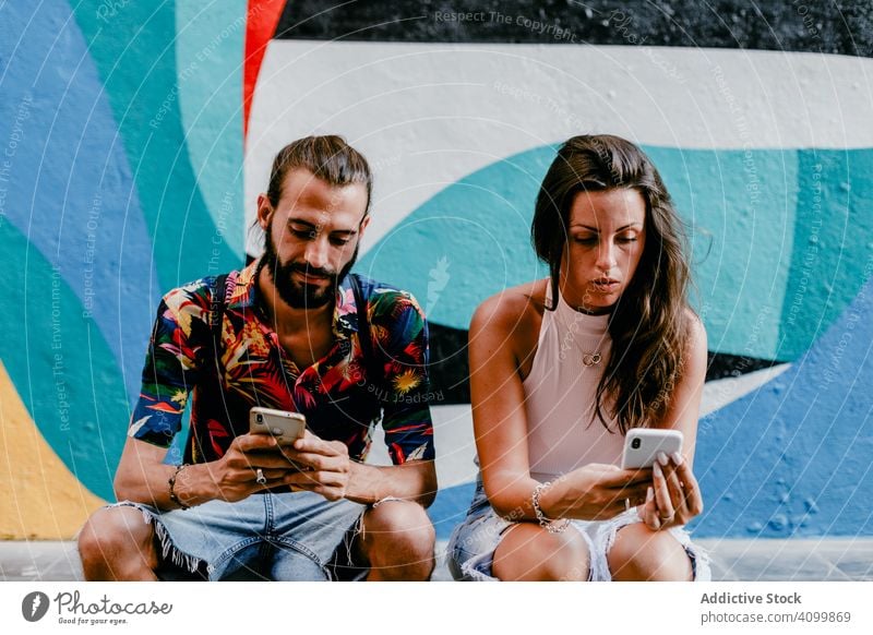 Paar sitzt auf dem Boden und surft auf dem Smartphone Freund Großstadt Sommer reisen schlendern Zusammensein Feiertag Straße erkunden Urlaub urban ethnisch