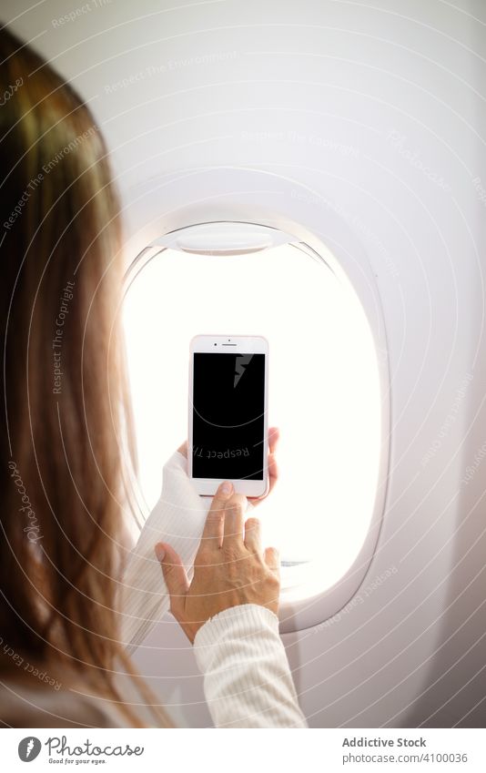 Frau schaltet Smartphone in der Nähe des Fensters im Flugzeug ein Ebene benutzend Browsen Surfen Mobile Telefon Passagier Ausflug Gerät Apparatur Urlaub