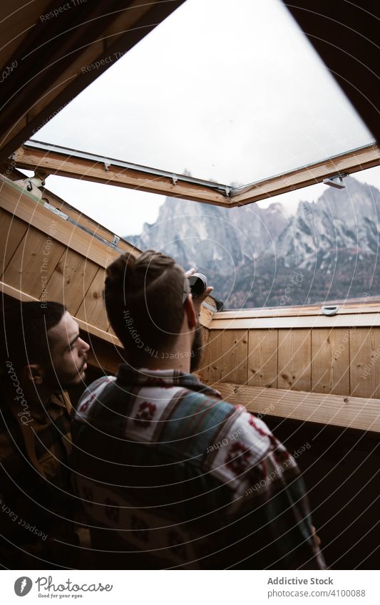 Männer in Freizeitkleidung genießen den Blick aus dem Deckenfenster Ansicht Zimmerdecke Fenster Deckenbeleuchtung modern Holz im Inneren Raum Haus hölzern