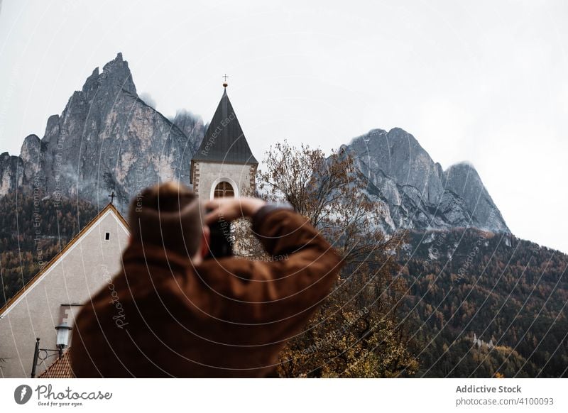 Männlicher Reisender, der ein Foto von Natur und Kirche auf der Kamera macht Tourist unter Fotokamera Gebäude Landschaft Berge Dolomiten Italien Wald Klippe