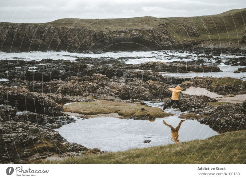 Mann springt über Meerwasserpfützen am felsigen Ufer Pfütze Küste MEER springen Wasser Felsen wolkig Nordirland Pool Landschaft Berge u. Gebirge Stein Natur