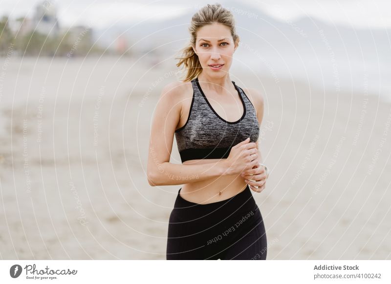 Läuferin in modischer Sportkleidung joggt an ruhiger, sandiger Küste Frau Joggen Strand springend Sommer Gesundheit ausarbeitend Übung Meer Aktivität Training