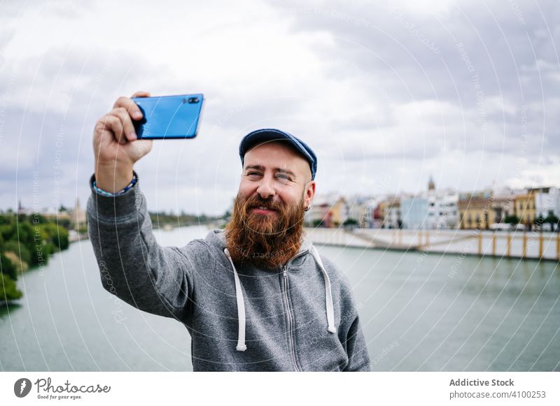 Zufriedener männlicher Tourist, der ein Selfie mit seinem Smartphone am Kai macht Herstellung unter Foto Mobile Telefon benutzend Browsen Frieden Zeichen