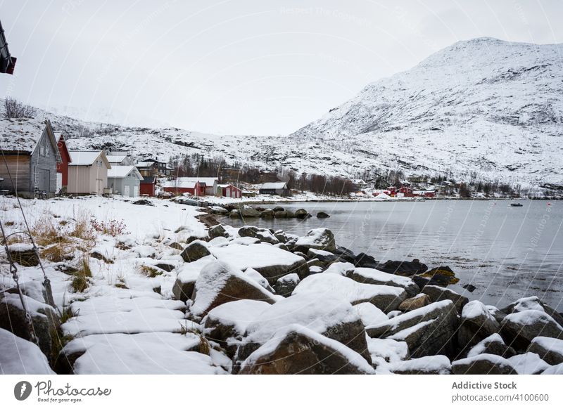 Ruhiger See vor schneebedeckten Hügeln bei kaltem, bedecktem Wetter Fjord Winter Ufer Wasser Norwegen ersfjordbotn Hochland Windstille verschneite Strand