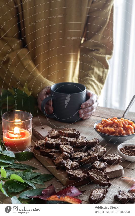 Eine Person genießt ein heißes Getränk und Kekse trinken warm heimwärts Kerze gemütlich Blatt Dessert Tisch Becher Morgen Gebäck Komfort Biskuit Tasse Pullover