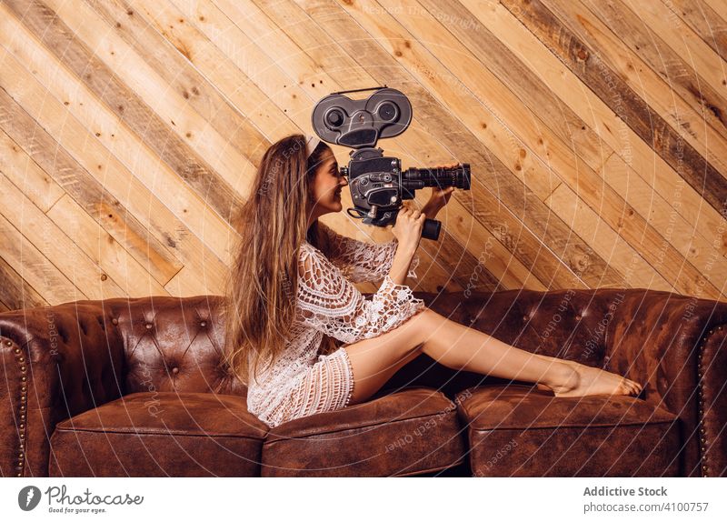 Junge Frau, die ein Video mit einer alten Kamera aufnimmt Fotokamera Kino Videographie Videofilmer Holz Liege altehrwürdig Antiquität Gerät Kamerafrau Konzept