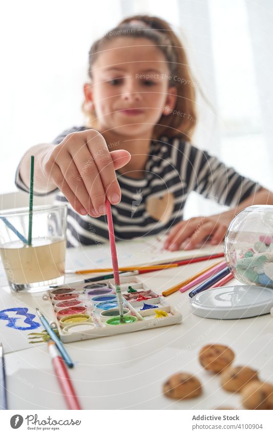 Mädchen malt mit Aquarellfarben zu Hause Farbe Wasserfarbe Pinselblume heimwärts Kunst kreativ Bildung Tisch sitzen Kind farbenfroh Pigment Farbstoff Werkzeug