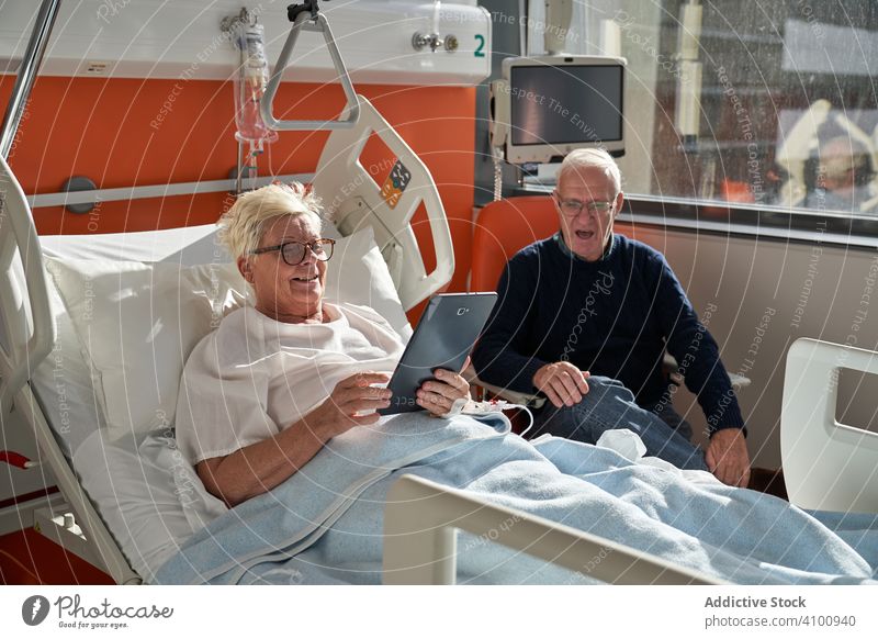 Älteres Ehepaar benutzt Geräte auf der Krankenhausstation Paar Station geduldig Besucher benutzend Tablette Smartphone Senior medizinisch Pflege Mann Frau