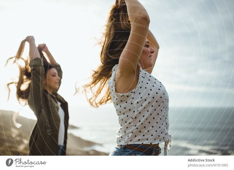 Glückliche weibliche Reisende genießen die Freiheit am Meer Frauen Seeküste Brise frisch fliegendes Haar Schwester stehen Harmonie Landschaft Zusammensein
