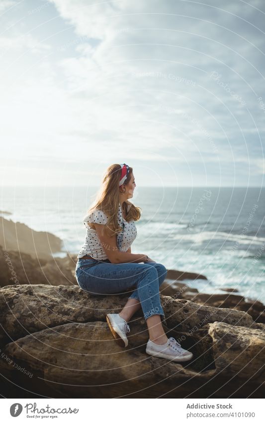 Nachdenkliche Frau auf einem Stein sitzend mit Blick auf eine Meereslandschaft verträumt Küste besinnlich Horizont Freiheit Inspiration Harmonie Seeküste Felsen