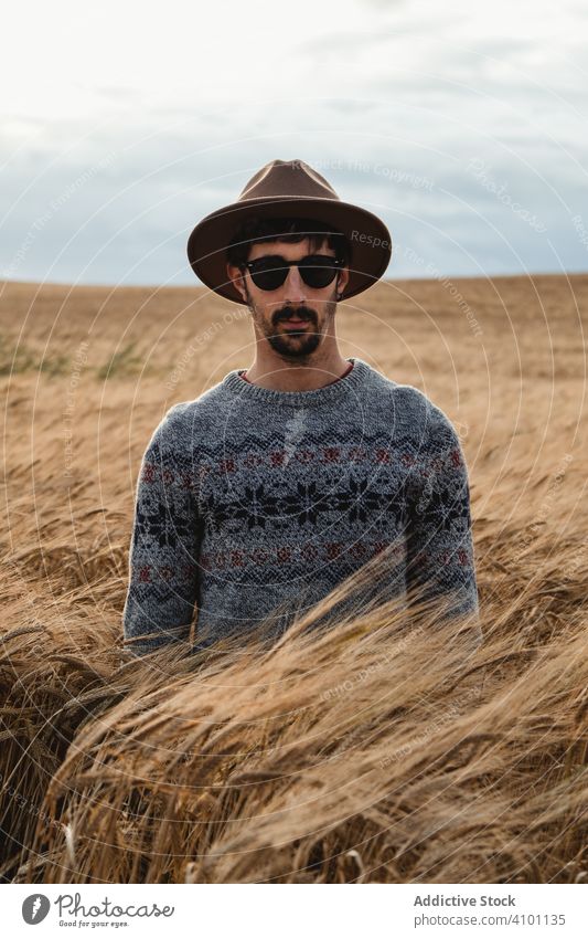 Mann steht auf einem trockenen Feld und schaut in die Kamera laufen Bauernhof Sommer Natur sonnig tagsüber jung ländlich rustikal Ackerbau Sämlinge Setzlinge
