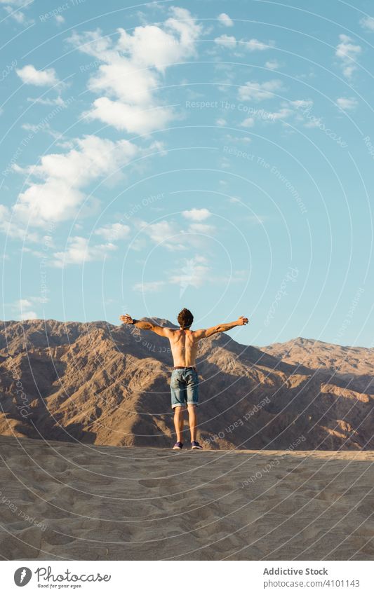 Rückenansicht eines aktiven jungen Mannes ohne Hemd, der den Wind im trockenen Death Valley genießt wüst Dunes reisen nackter Torso Gießen strecken Urlaub Regie