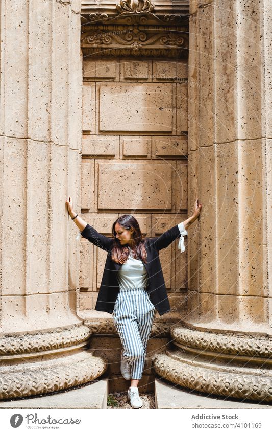 Frau lehnt auf dem Bürgersteig zwischen hohen massiven Säulen und blickt nach unten in San Francisco Spalte antik geometrisch Architektur Park abstützen