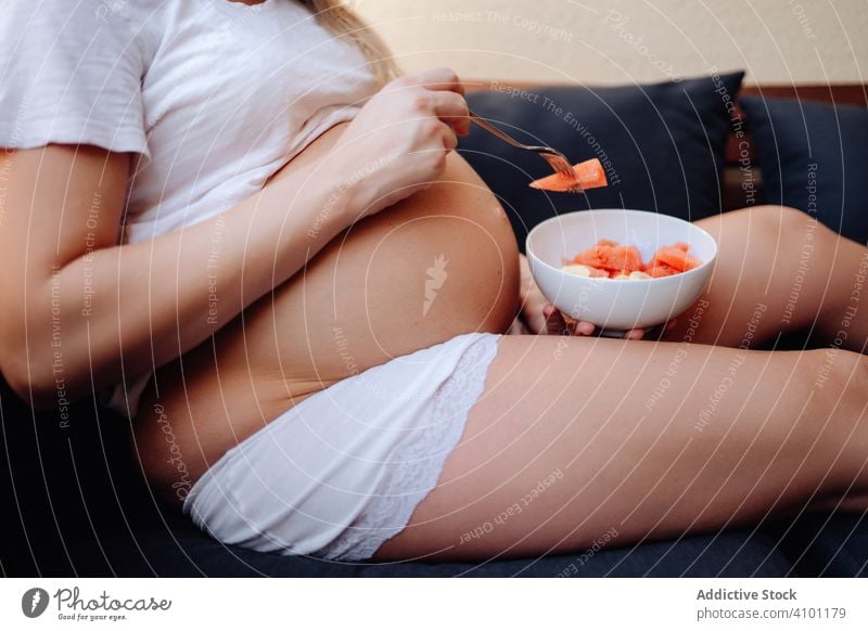Gesichtslose schwangere Frau isst Früchte mit Gabel Frucht Schwangerschaft Mutterschaft Lebensmittel Baby Ernährung Bauch Gesundheit jung frisch erwarten Pflege
