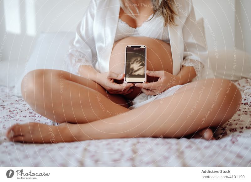 Gesichtslose schwangere Frau zeigt Bild von Ultraschalluntersuchung Schwangerschaft manifestieren Ultraschall-Scan Smartphone heimwärts Mutterschaft Baby Bauch