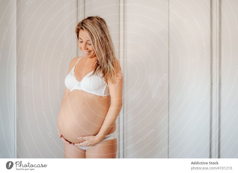 Lächelnde schwangere Frau, die ihren nackten Unterleib berührt Schwangerschaft berühren Mutterschaft Baby Bauch Gesundheit jung erwarten Pflege Lifestyle weiß