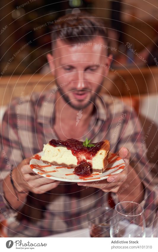 Ein Mann in Freizeitkleidung nimmt ein Stück Kuchen im Restaurant Dessert männlich Lebensmittel süß Feier Party Tisch Geburtstag festlich lässig Typ Sitzen