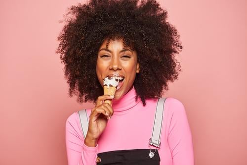 Lustige Frau mit Eiscreme, die in die Kamera schaut Speiseeis Spaß Glück beschmiert Lippen rosa Lachen heiter aufgeregt Essen Afroamerikaner schwarz stehen