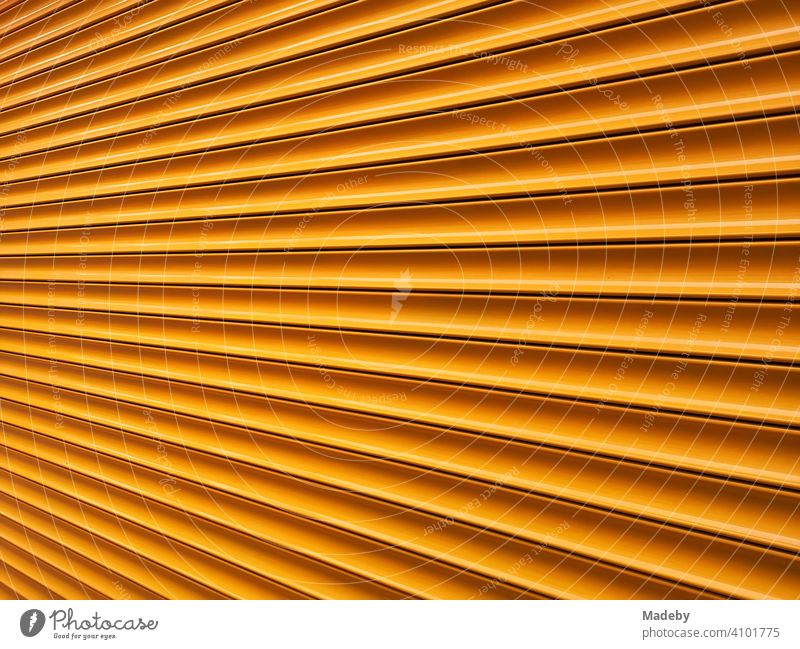 Modernes Rolltor in leuchtendem Orange in Alacati bei Cesme am Mittelmeer in der Provinz Izmir in der Türkei Industrietor Rollladen Profil Hintergrund