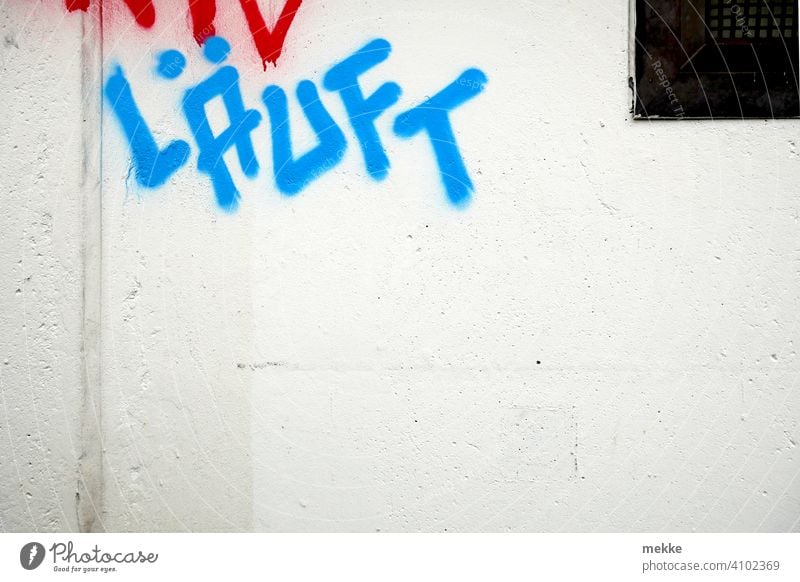 Läuft Grafitti auf weißer Hauswand grafitti schrift blau wandmalerei Text botschaft farbe Deutsch gesprayt grafitto mauer urban stadt slogan straße