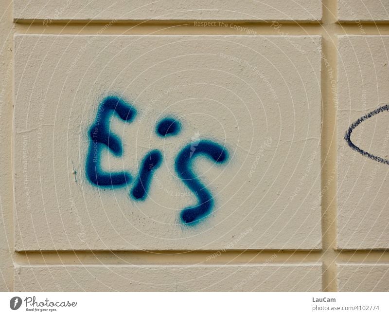 Blauer Schriftzug „Eis“ auf heller Hausfassade Buchstaben Wort Fassade blau gelb Wand Graffiti Farbfoto Straßenkunst Schmiererei Mauer Text Schriftzeichen