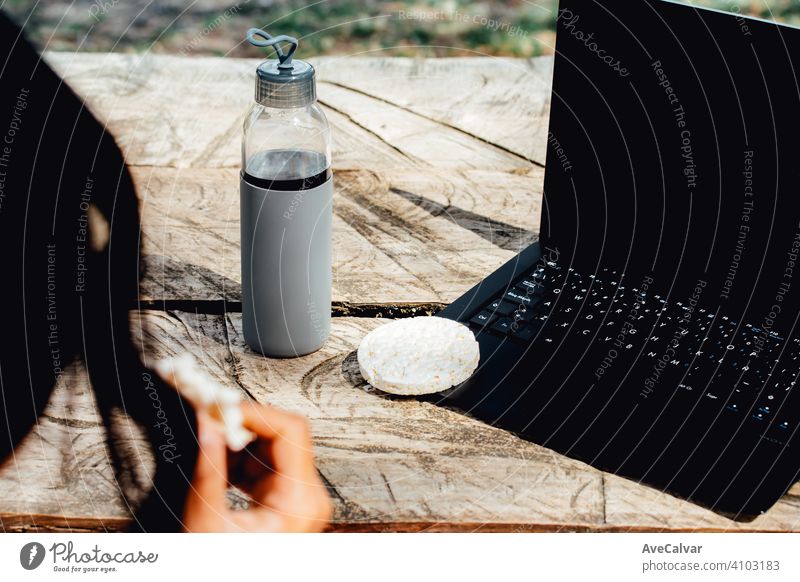 Eine Nahaufnahme von einem Laptop eine Wasserflasche und gesundes Essen über einen Holztisch Stock Kunstturnen im Innenbereich Meditation online Pilates Seminar