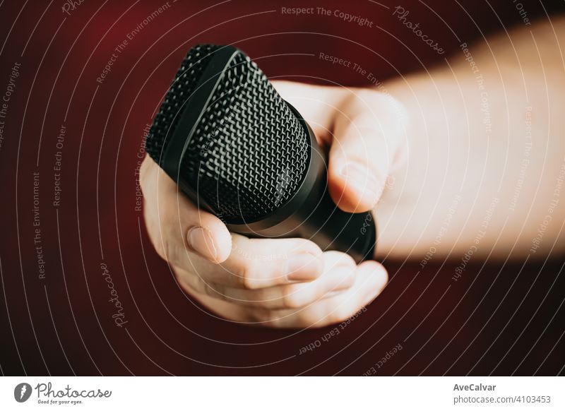 Eine Hand, die nach einem Mikrofon greift, über einem roten Hintergrund Aufzeichnen Audio Technik & Technologie Musik professionell Klang Radio Aufnahme Atelier