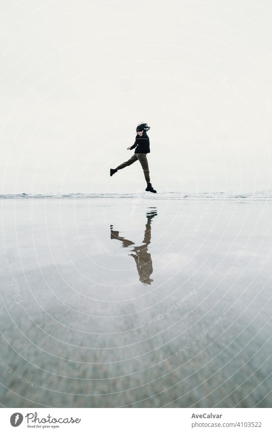 Junge Frau springen am Strand mit einer Reflexion über das Wasser mit Kopie Raum Freiheit Konzept Person Meer Einsamkeit Senior einsam Erholung Atem sorgenfrei