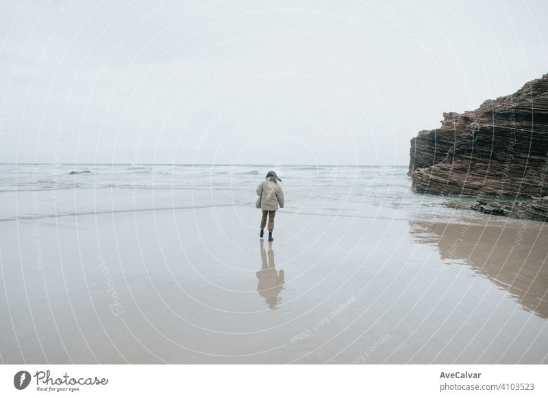 Eine junge Frau, die am Ufer des Strandes während eines bewölkten Tages spazieren geht, mit Kopie Raum und Freiheit Konzept Person Meer Einsamkeit Senior einsam