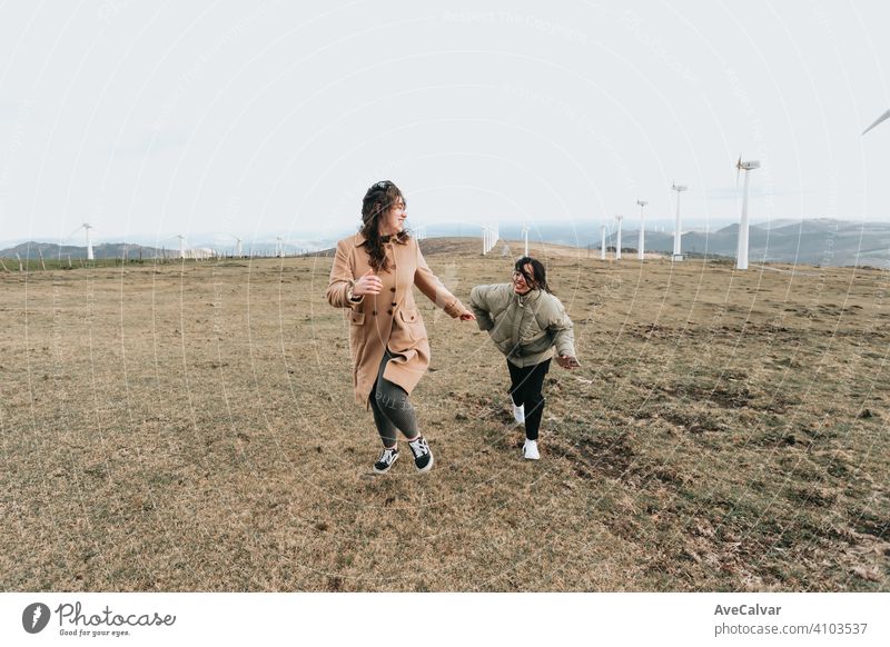 Ein Paar von zwei Frauen laufen und lächelnd Freiheit und Glück Konzept in der Nähe von Windmühlen während eines bewölkten Tages Person lesbisch Kopierbereich