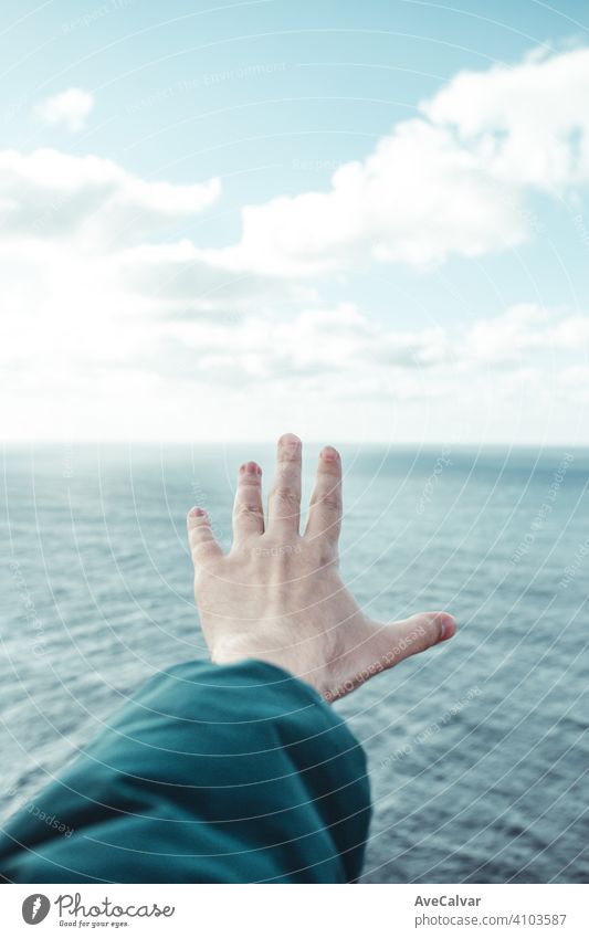 Hand eines Mannes über einen kristallklaren Horizont des Ozeans mit weißen Wolken mit Kopie Raum, Inspiration und Freiheit Konzept Paradies Frieden