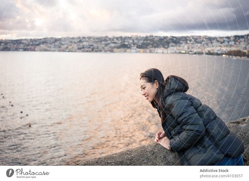 Frau im Urlaub in warmer Kleidung genießt den Sonnenuntergang am Meer Meeresufer Cloud Himmel Lächeln genießen Lachen Freude reisen Tourismus