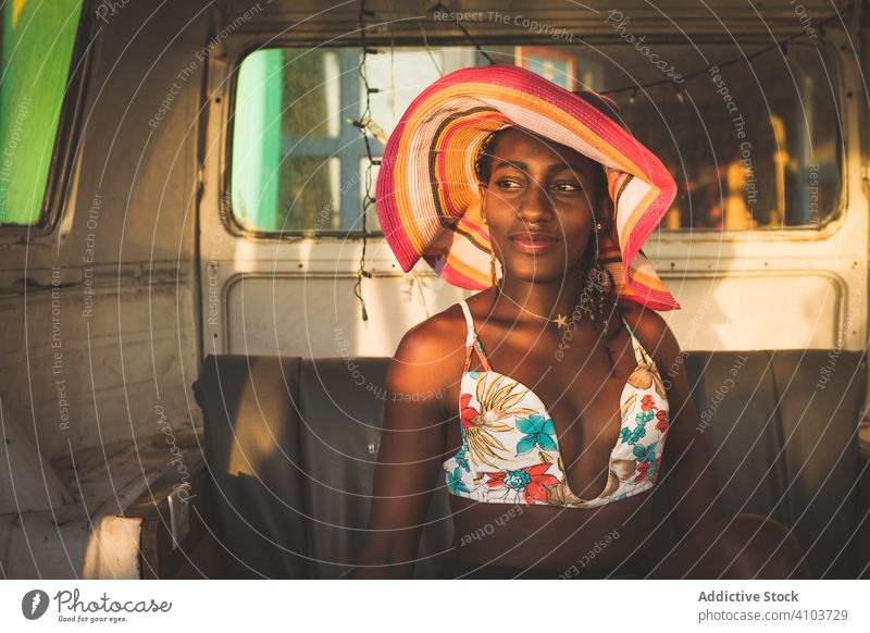 Glückliche afroamerikanische Frau sitzt hinter dem Steuer eines Autos Laufwerk PKW Kleintransporter altehrwürdig retro Hut Stil Lächeln genießen Spaß Rad Outfit