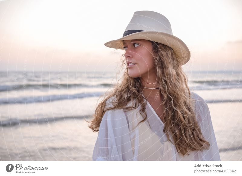 Charmante Frau in leichtem weißen Kleid am gewellten Strand MEER reisend Seeküste Tourismus charmant Urlaub Hut lockig Feiertag Sommer Freiheit Reise jung