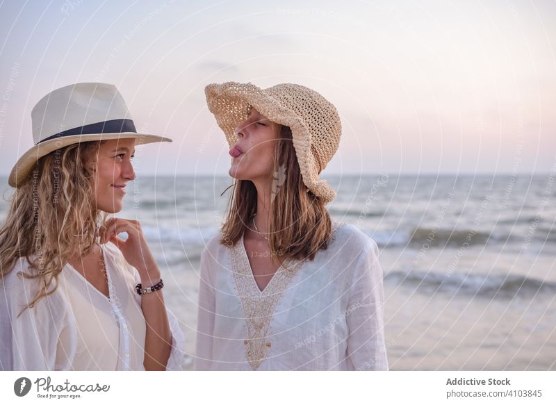Lächelnde Freundinnen in Sommerkleidung barfuss im Wasser am Strand Frauen MEER Barfuß reisend Seeküste charmant Urlaub Hut lockig Feiertag Zusammensein